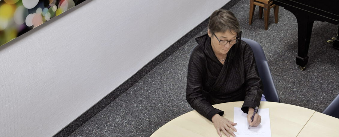 Susanne-Kazemieh-sitzend-und-schreibend-am-Tisch