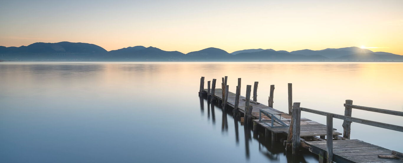 holzsteg-an-einem-see-mit-aufgehender Sonne