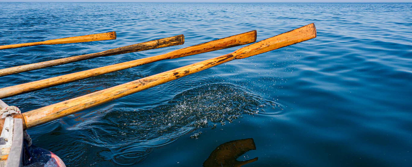 vier-lange-schmale-paddel-schweben-gleichmaessig-ueber-dunkelblauer-meeresoberflaeche